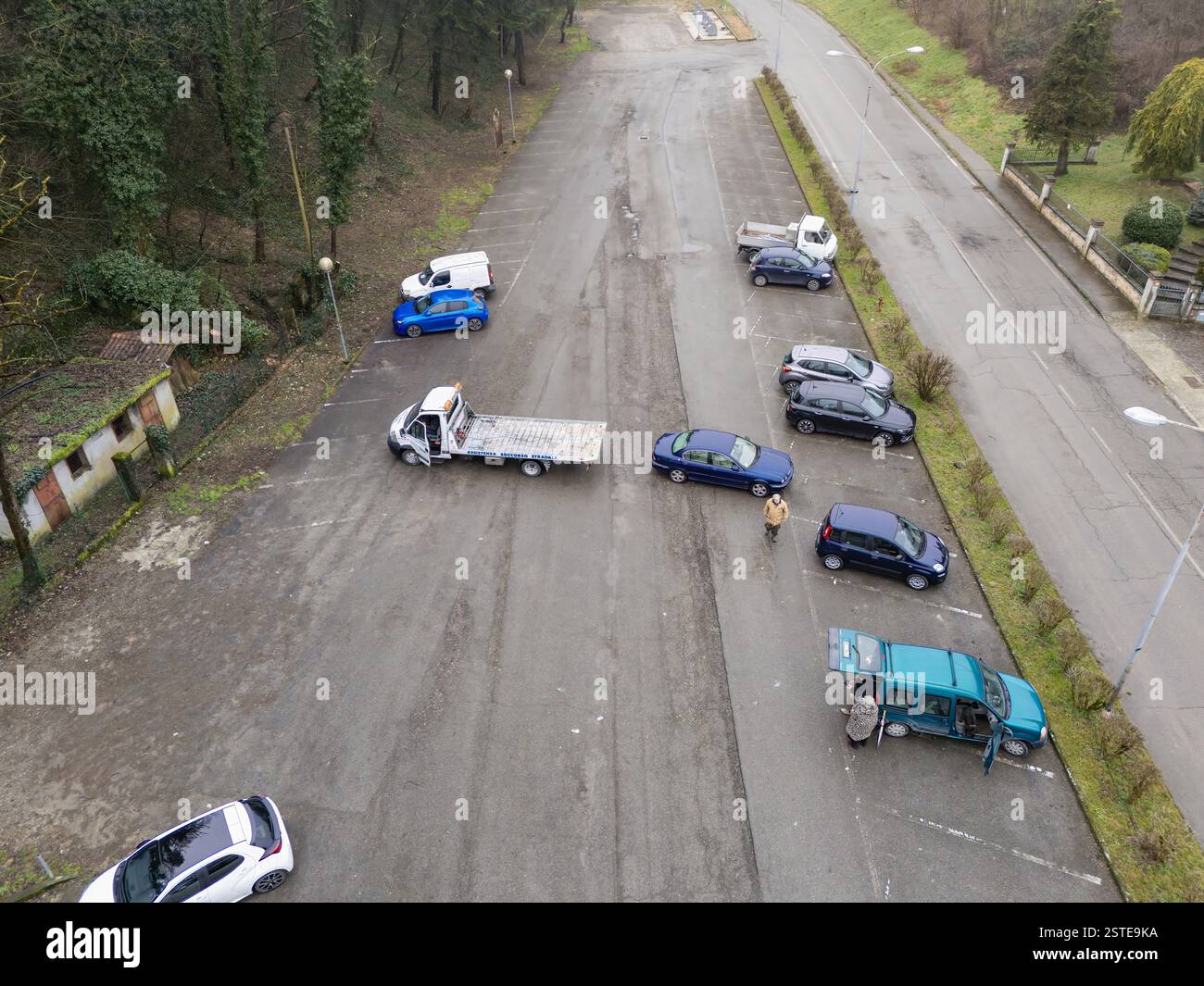 Castell'Arquato, PC, Italia - 5 febbraio 2024 Vista aerea di un parcheggio con autocarro e meccanici che ispezionano varie auto, tra cui una S blu Foto Stock