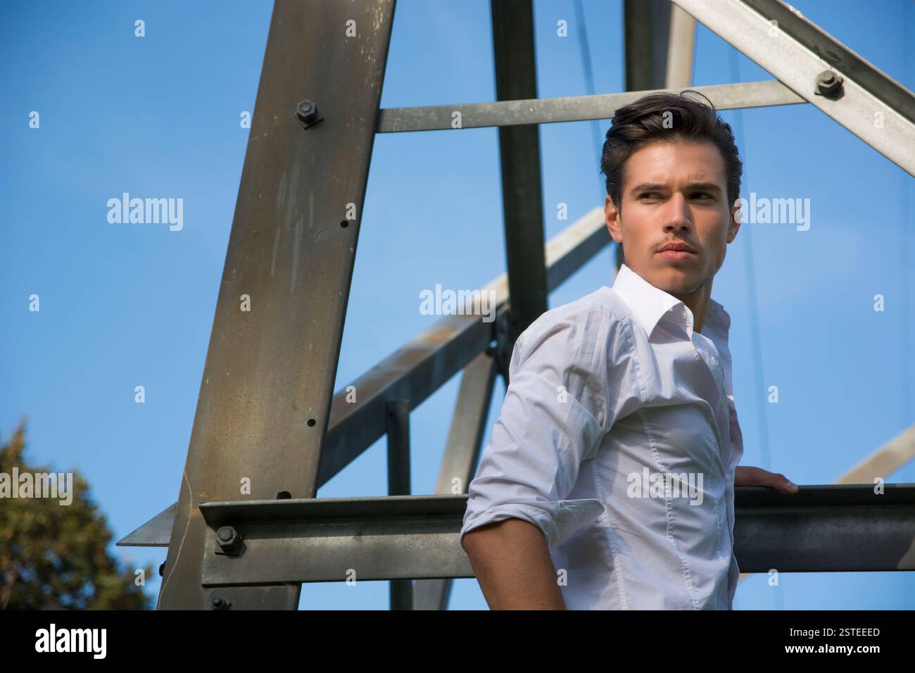 Bel giovane appeso a un traliccio elettrico metallico Foto Stock