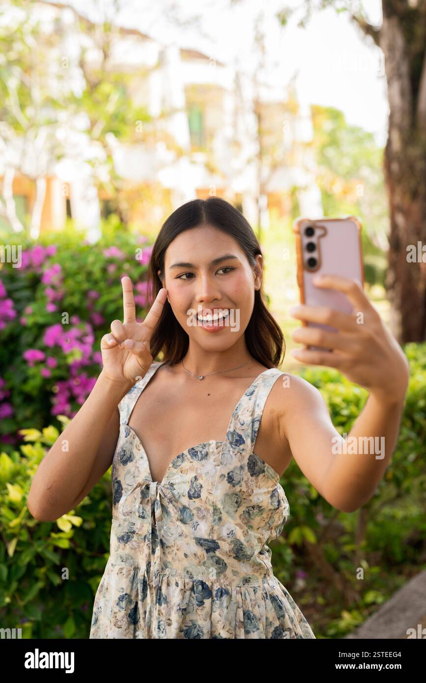 Giovane donna asiatica che usa il telefono all'aperto Foto Stock