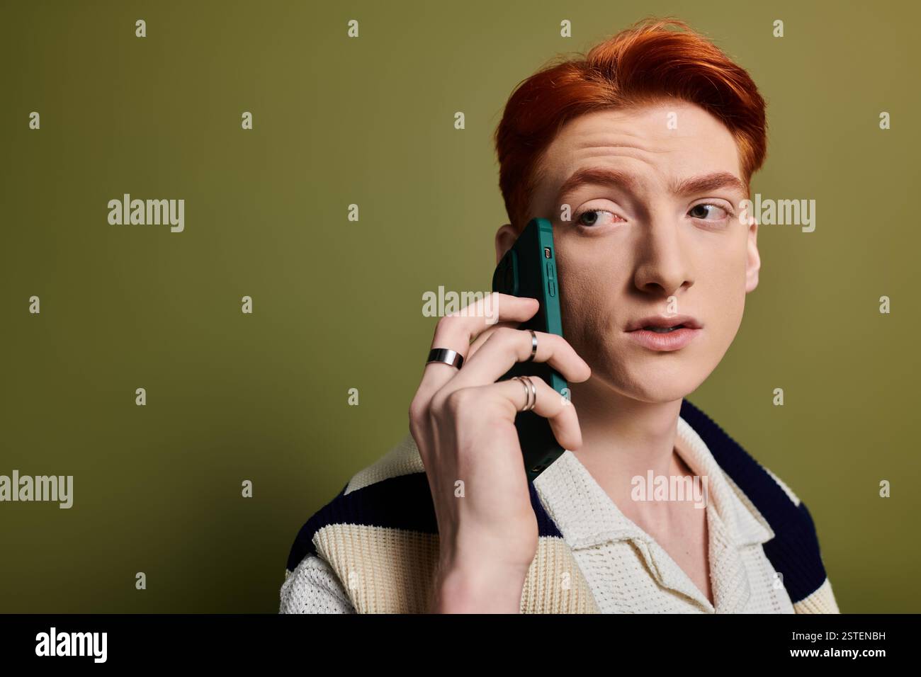 Un giovane con caratteristiche sorprendenti parla emotivamente al telefono, mostrando una profonda espressione. Foto Stock