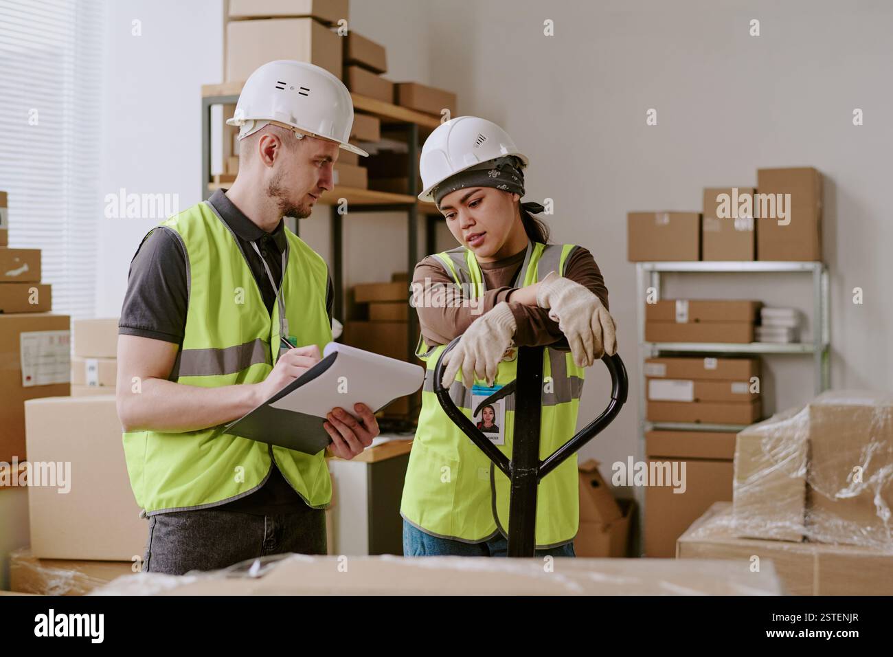 Colleghi che esaminano i dettagli della spedizione durante le operazioni di magazzino il dipendente che tiene documenti e discute della logistica per la gestione dell'inventario Foto Stock
