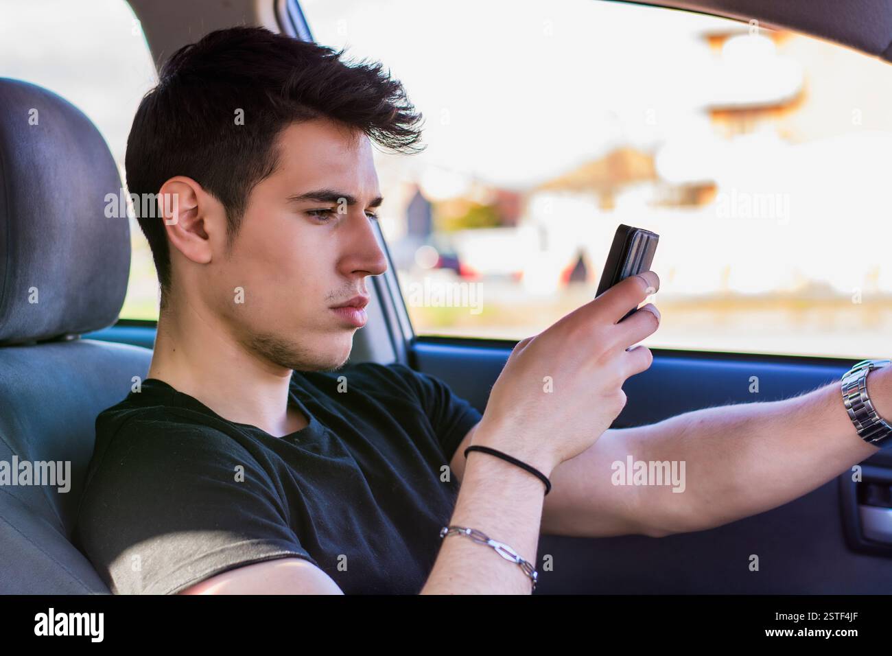 Distratti Giovane utilizzando il telefono cellulare mentre si è alla guida di un veicolo Foto Stock