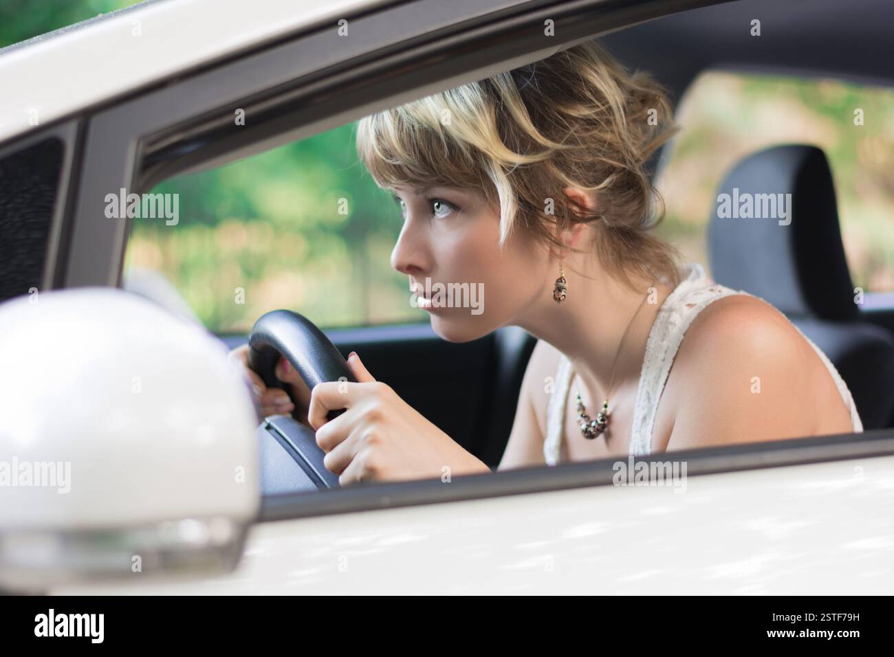 Giovane donna di imparare a guidare la macchina e piegatevi in avanti Foto Stock