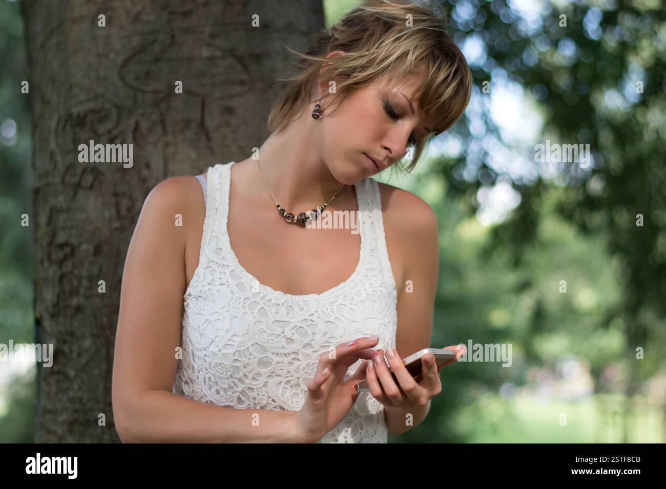 Attraente ragazza bionda all'aperto tramite telefono cellulare Foto Stock