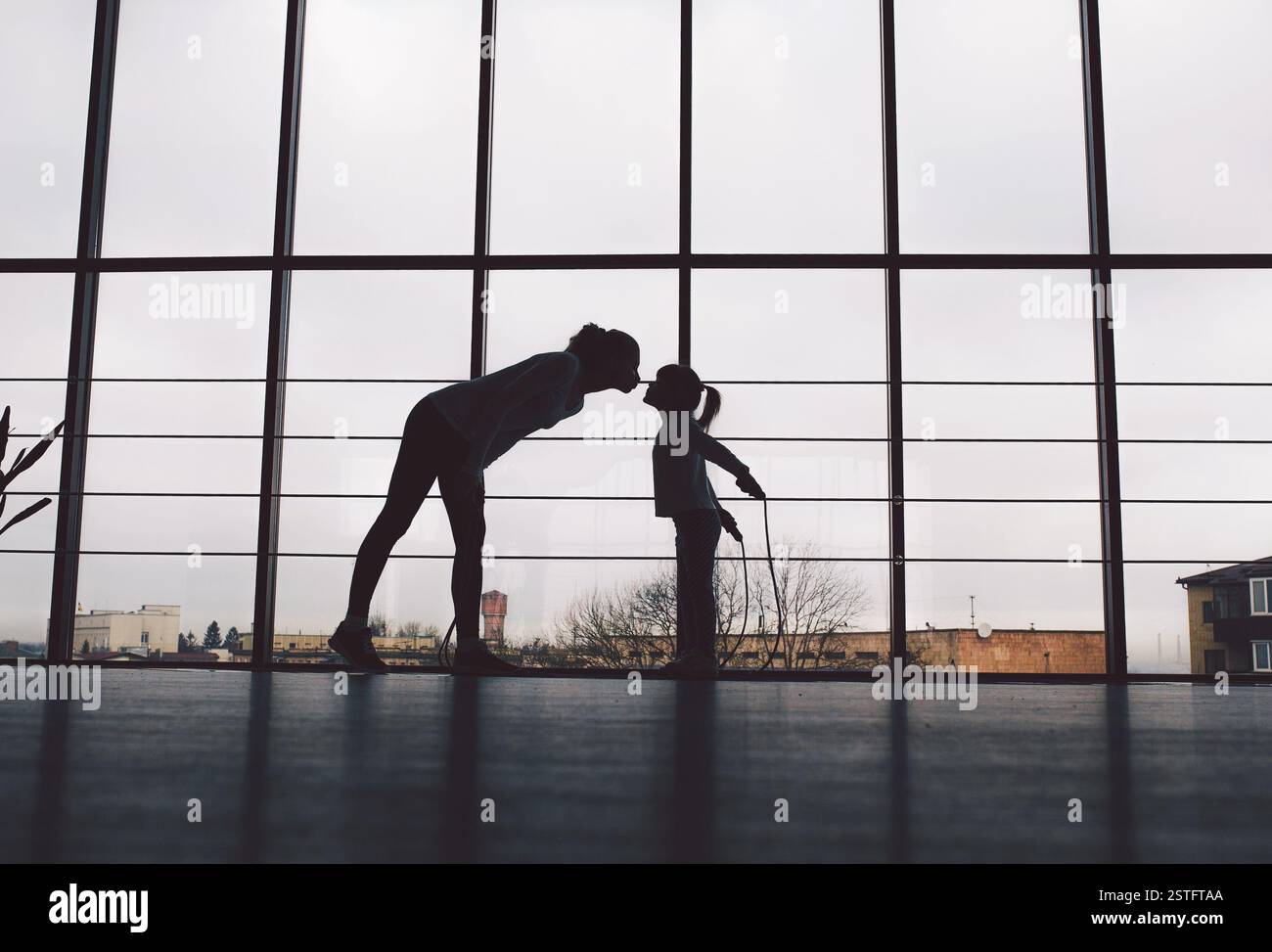 Silhouette di madre e figlia in palestra.Kiss Foto Stock