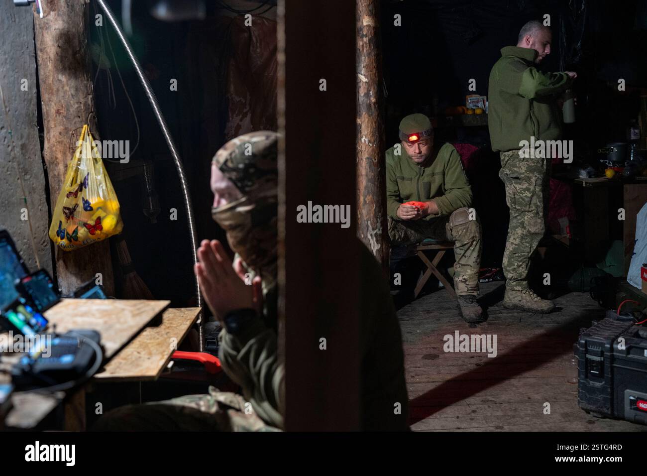 Ucraina. 22 dicembre 2024. All'interno di un bunker sotterraneo, gli operatori di droni ucraini volano un drone per colpire le posizioni russe in prima linea. La guerra tra Ucraina e Russia ha dimostrato quanto i droni economici e sacrificabili, come il kamikaze o i modelli che lanciano bombe, stiano rimodellando la guerra. Questi droni consentono attacchi precisi e a basso costo e si sono dimostrati estremamente efficaci nell'interrompere le operazioni nemiche. Di conseguenza, stanno cambiando le strategie militari, segnalando un futuro in cui i droni svolgono un ruolo centrale nel combattimento, riducendo la dipendenza dalle armi tradizionali e costose. (Immagine di credito: © Miguel Cande Foto Stock