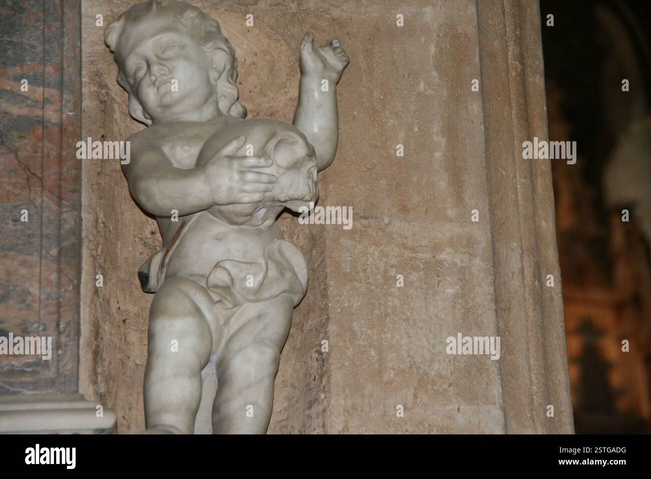 Una scena macabra di un cherubino che tiene un teschio su una tomba in una vecchia chiesa inglese. Foto Stock