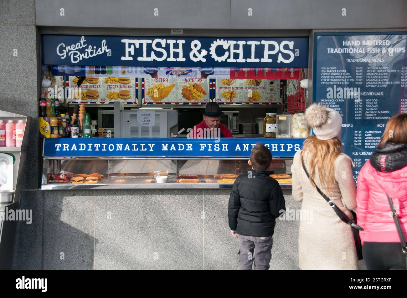 Una famiglia che sceglie un pasto a base di fish and chips da un negozio di alimentari vicino alla Torre di Londra, Regno Unito Foto Stock
