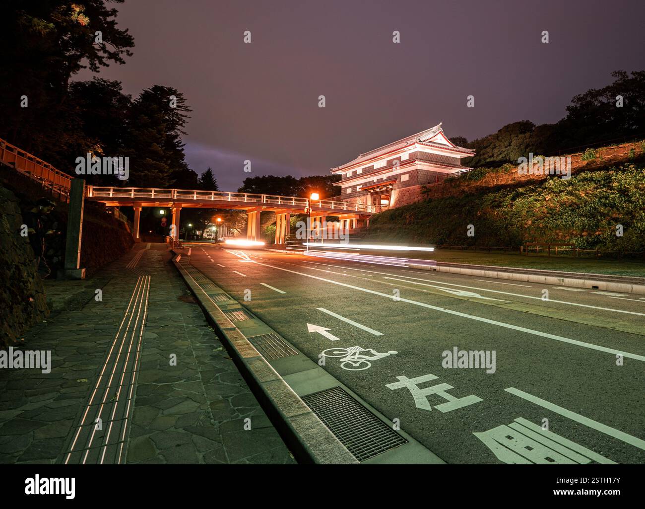 Un cancello storico splendidamente illuminato a Kanazawa, Giappone, catturato di notte con sentieri leggeri dai veicoli di passaggio. Foto Stock