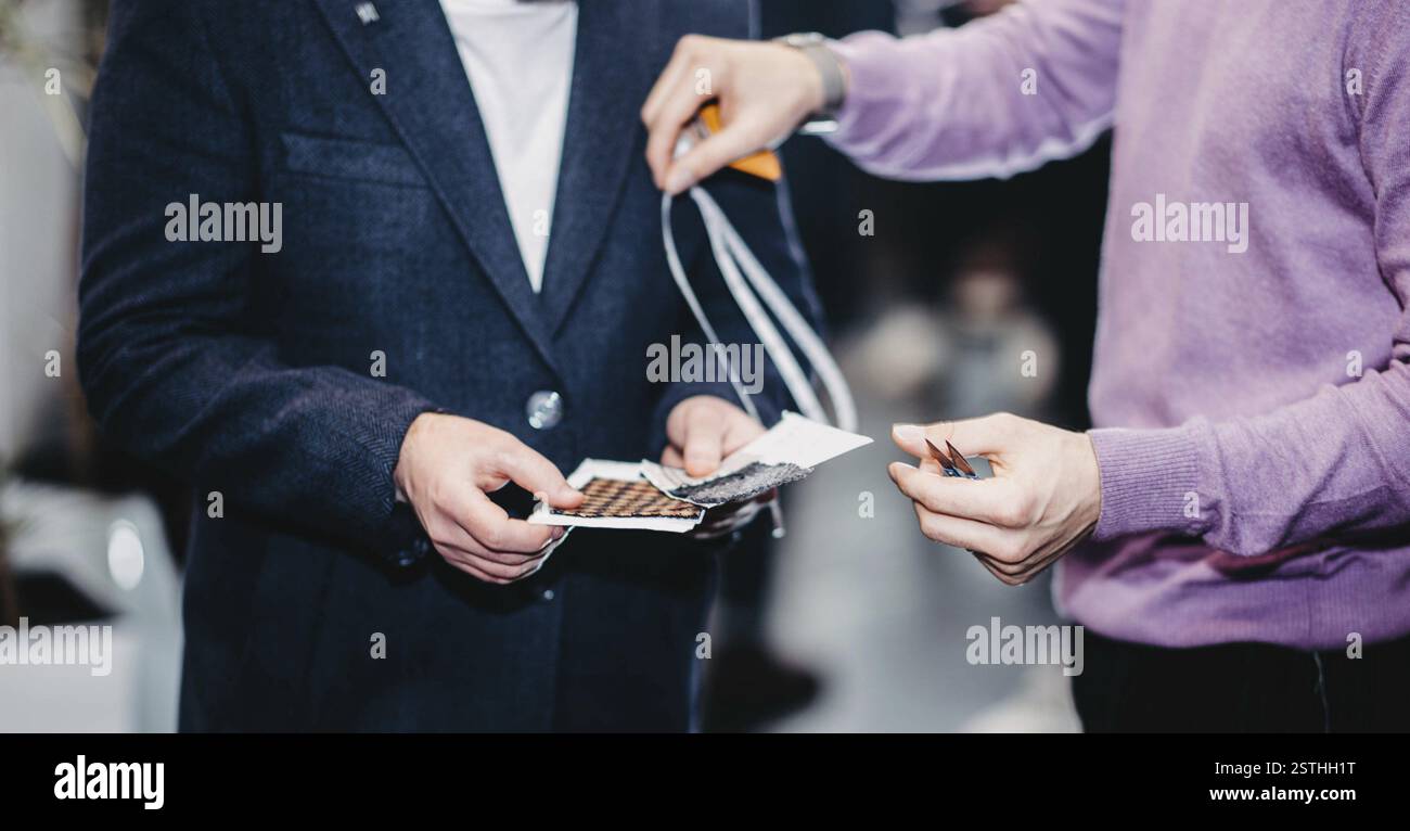 Due persone che tengono e discutono campioni di tessuto, suggerendo un ambiente aziendale formale Foto Stock