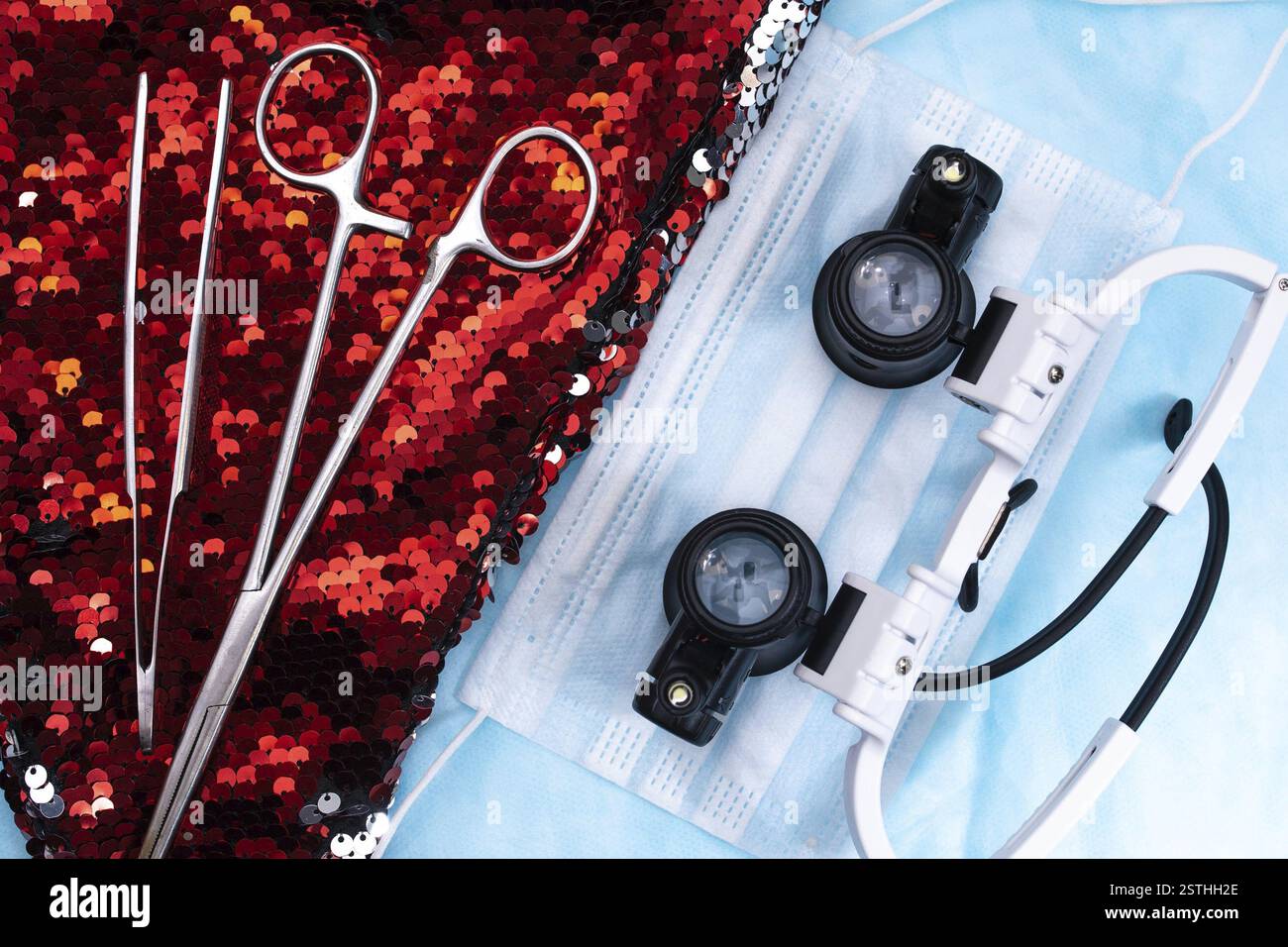 Strumenti chirurgici, occhiali di ingrandimento, e maschera su paillettes rosse, raffigurante un ambiente medico Foto Stock