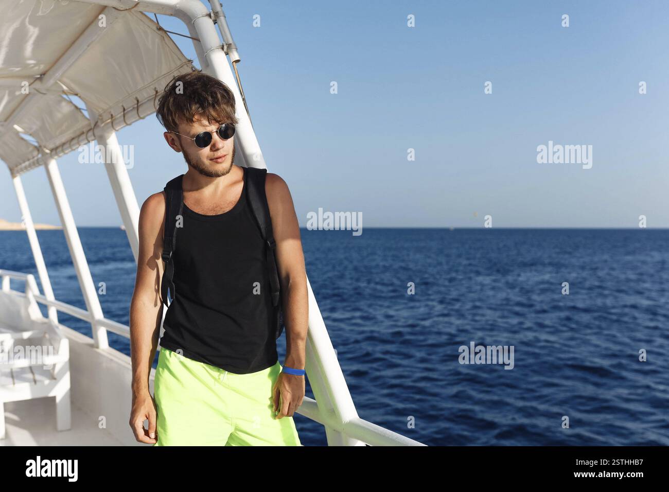 Uomo con occhiali da sole in piedi su una barca sullo sfondo di un oceano soleggiato Foto Stock