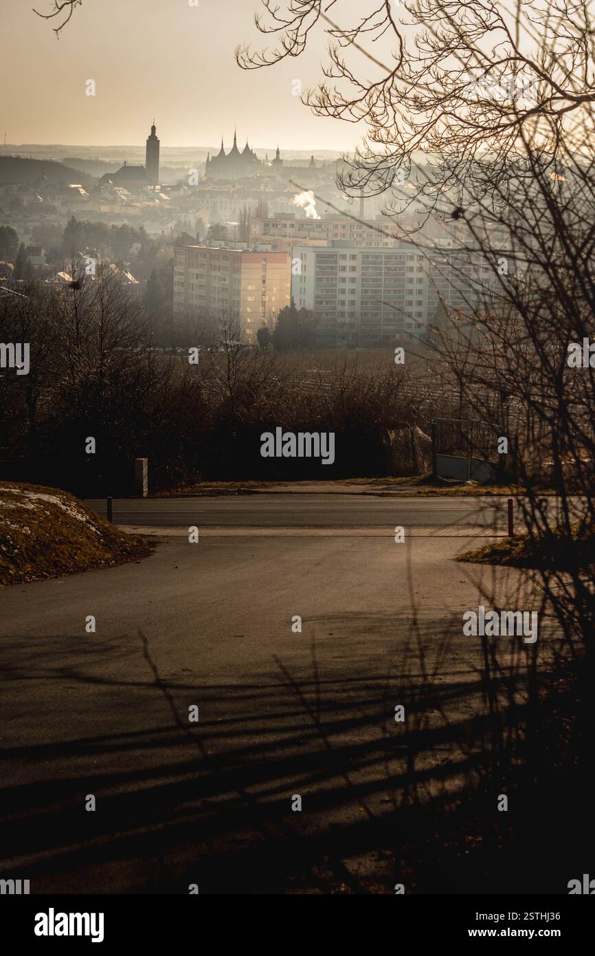 "Vista panoramica di Kutná Hora, Repubblica Ceca, con architettura storica e un'alba nebbiosa che creano un'atmosfera calda e dorata." Foto Stock