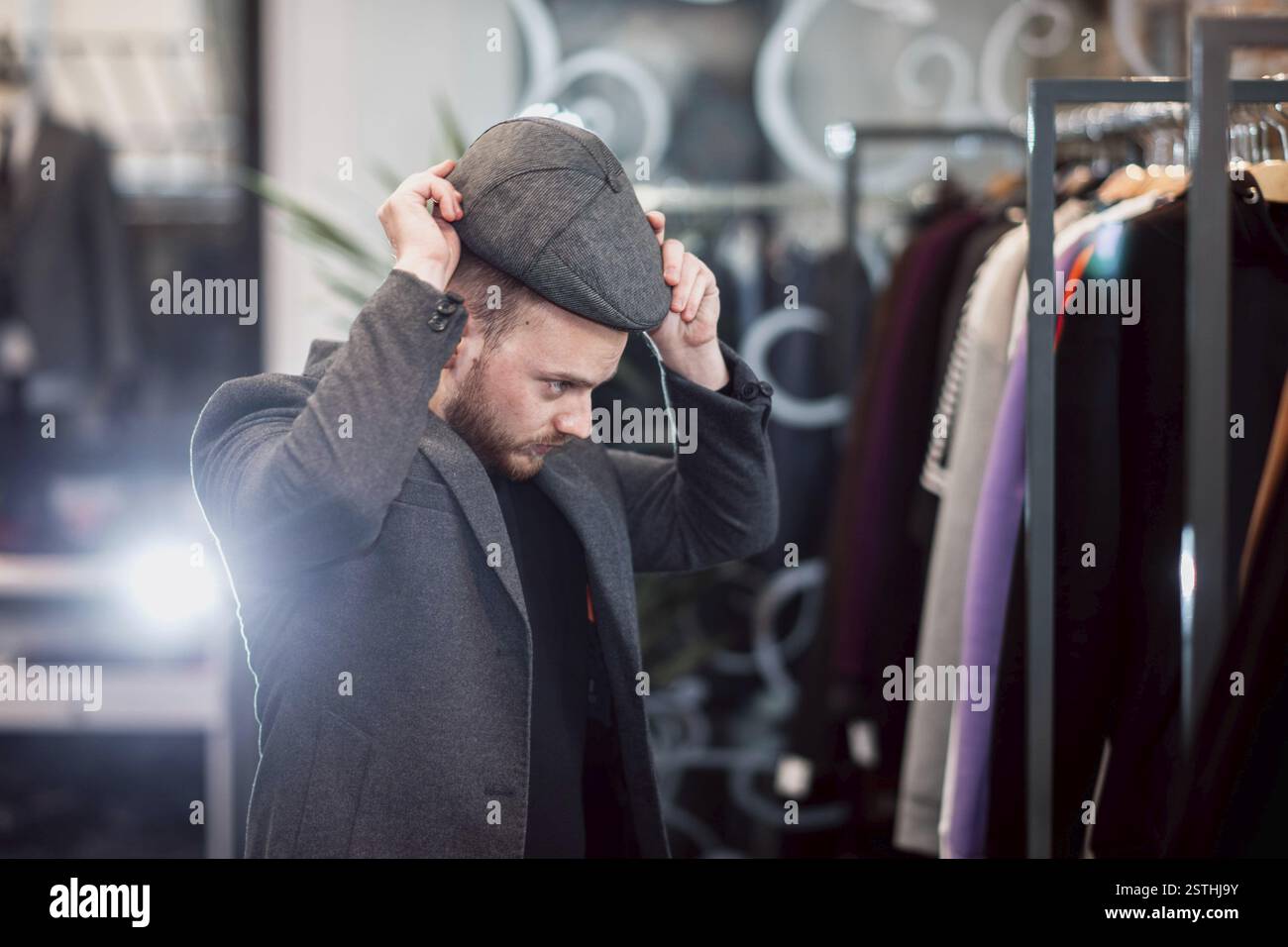 Persona che prova un berretto piatto in un negozio di abbigliamento alla moda Foto Stock