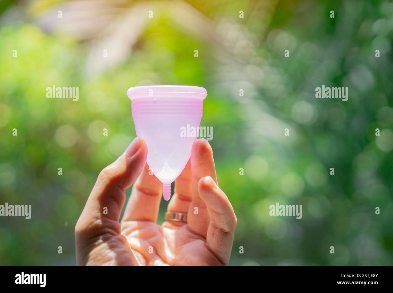 Periodo della donna, tazza mestruale in mano su un vero sfondo naturale, metodi moderni per giorni criptati. Concetto di prodotti ginecologici e igienici. Foto Stock