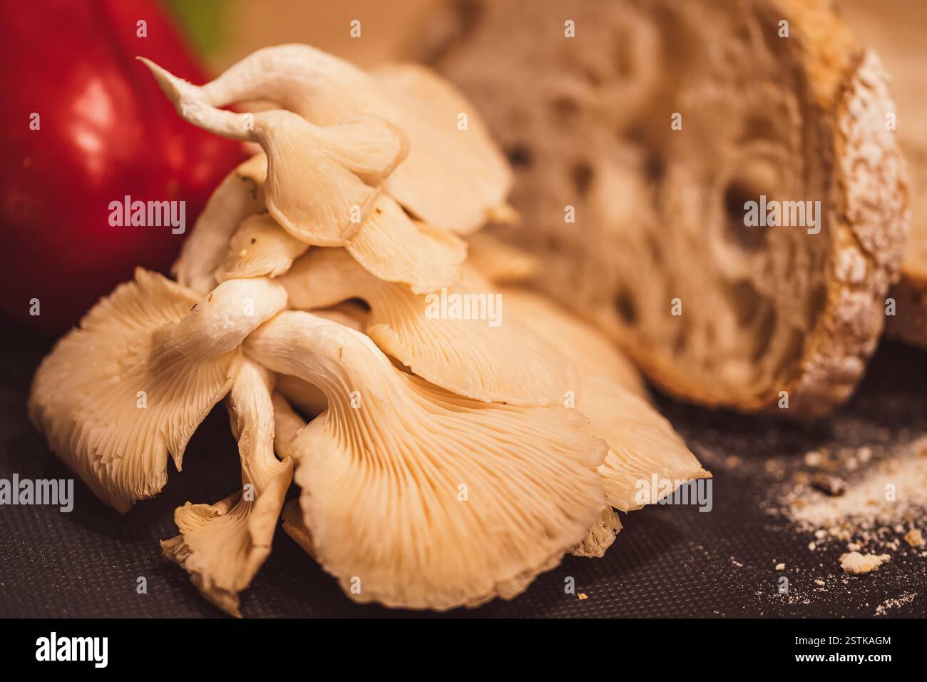 I funghi di ostrica con fette di pane e un pepe sullo sfondo creano un momento da fattoria a tavola. Evidenziando texture naturali e ingredienti freschi Foto Stock