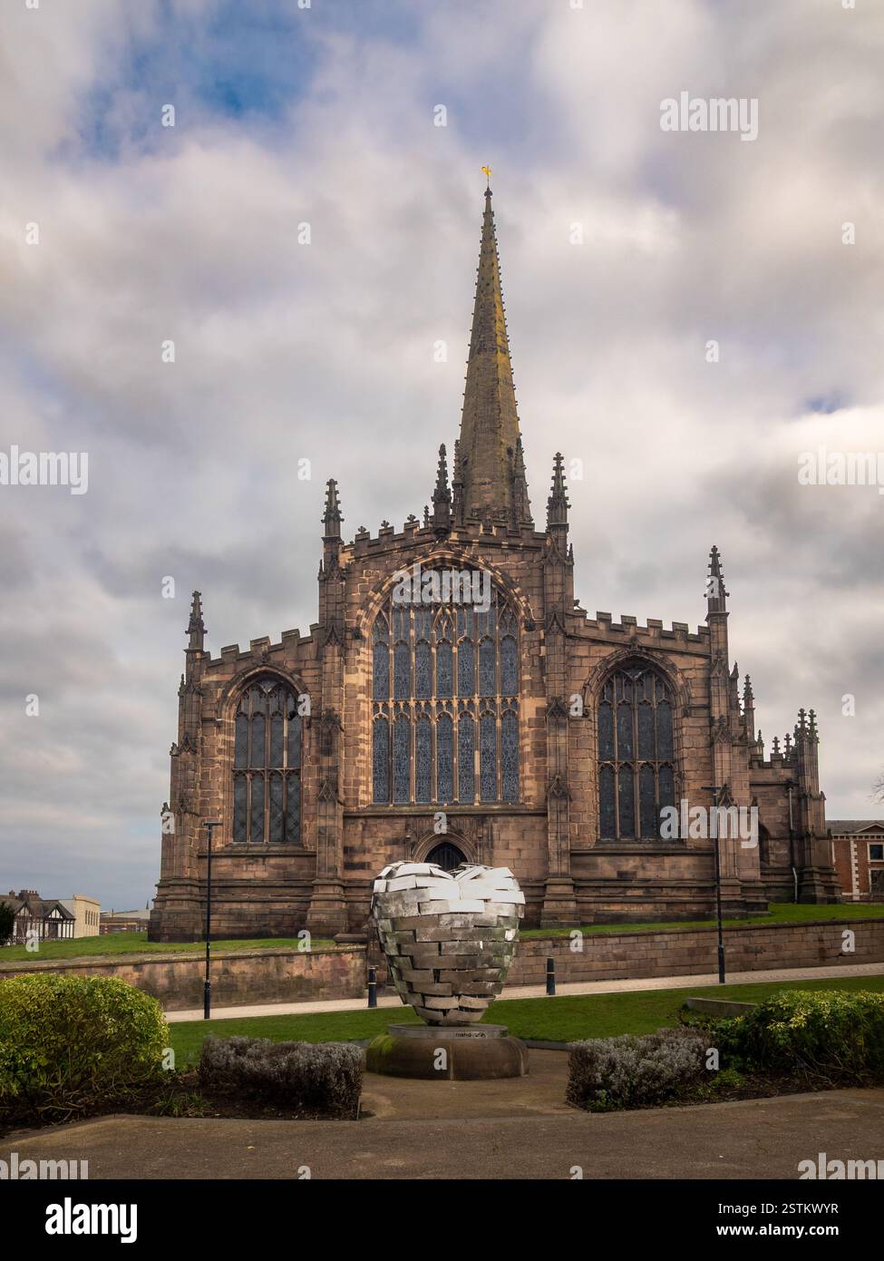 La facciata ovest del Rotherham Minster vista dai Minster Gardens, con la scultura Rotherham Heart of Steel in primo piano. South Yorkshire. REGNO UNITO Foto Stock