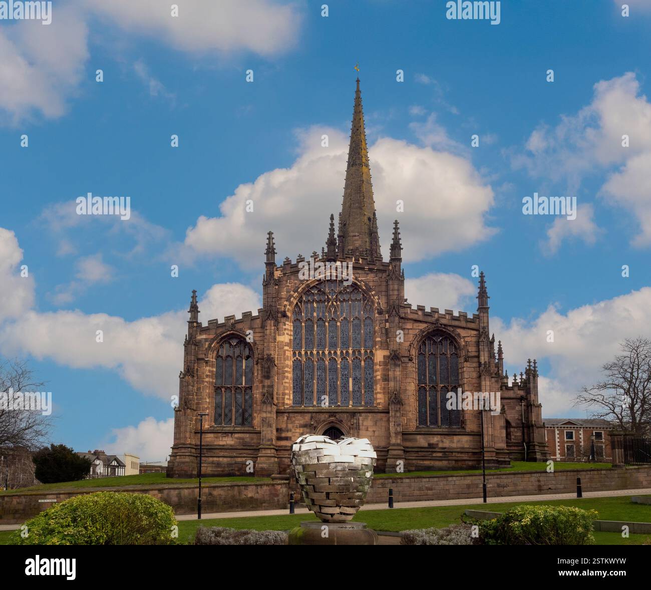 La facciata ovest del Rotherham Minster vista dai Minster Gardens, con la scultura Rotherham Heart of Steel in primo piano. South Yorkshire. REGNO UNITO Foto Stock
