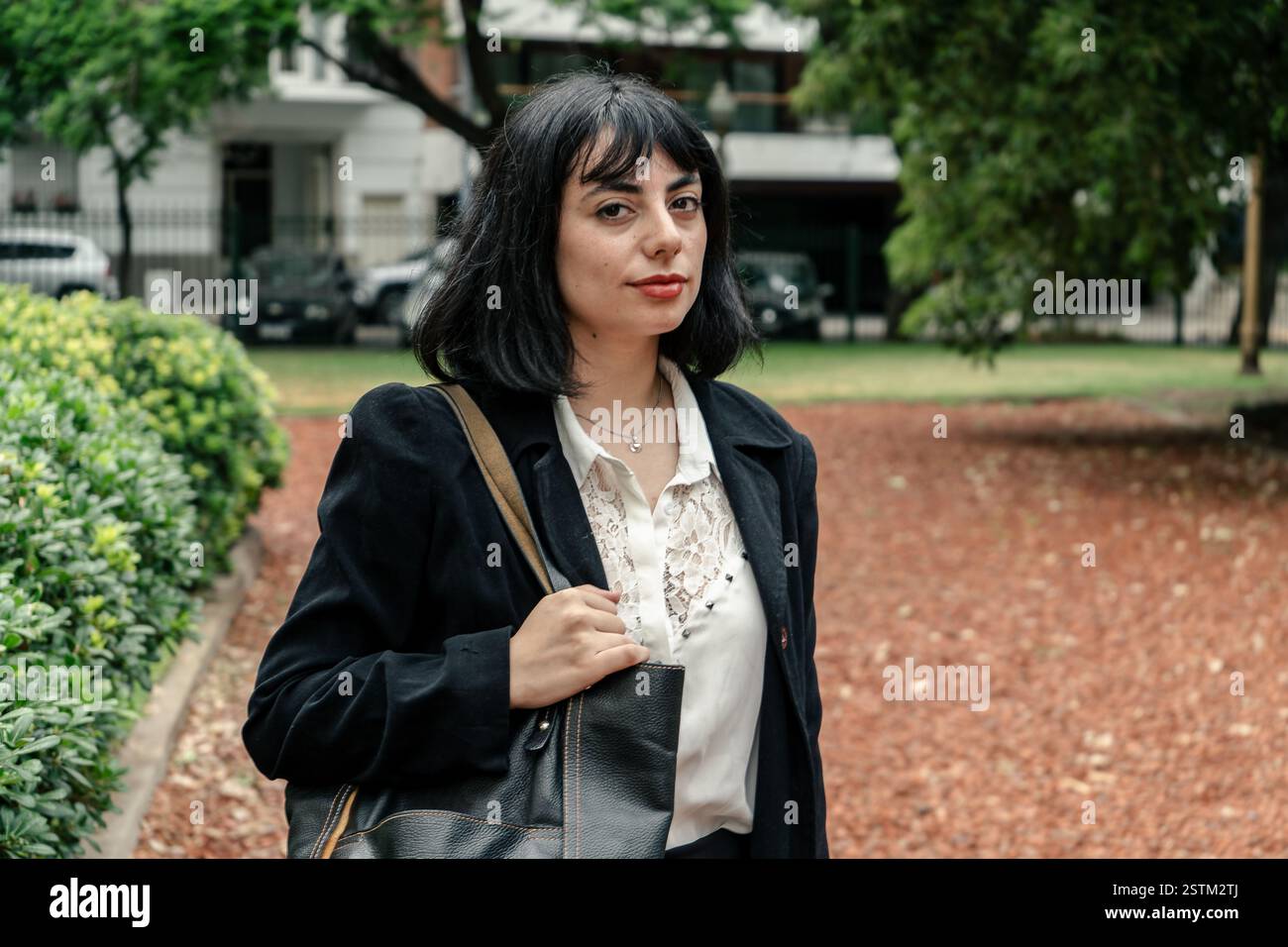 Elegante donna d'affari che cammina in un parco, incarnando fiducia e professionalità Foto Stock
