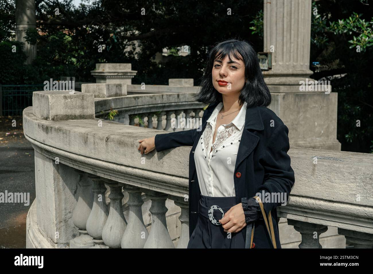 Elegante donna ispanica in posa in un classico ambiente urbano, che mette in mostra eleganza e sicurezza Foto Stock