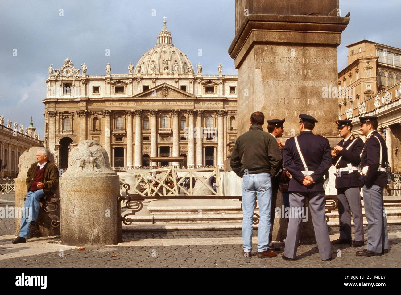 Carabinieri e gente del posto all'Obelisco Vaticano con la Chiesa di San Pietro in lontananza in Piazza San Pietro, città del Vaticano, Roma, Italia Foto Stock