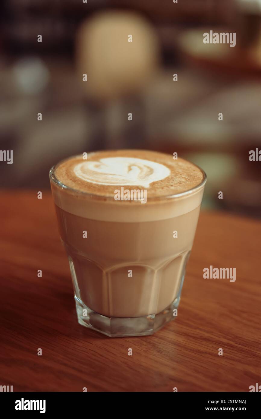 Cappuccino o caffè bianco piatto servito in un piccolo bicchiere sul tavolo nel caffè Foto Stock