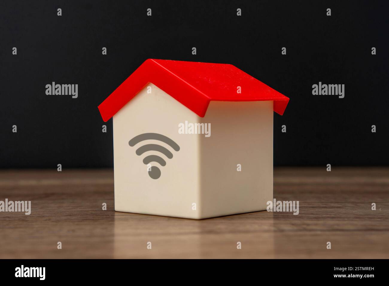 Una casa dei giocattoli e un simbolo del wi-fi su sfondo scuro. wifi domestico, concetto di Internet delle cose. Foto Stock