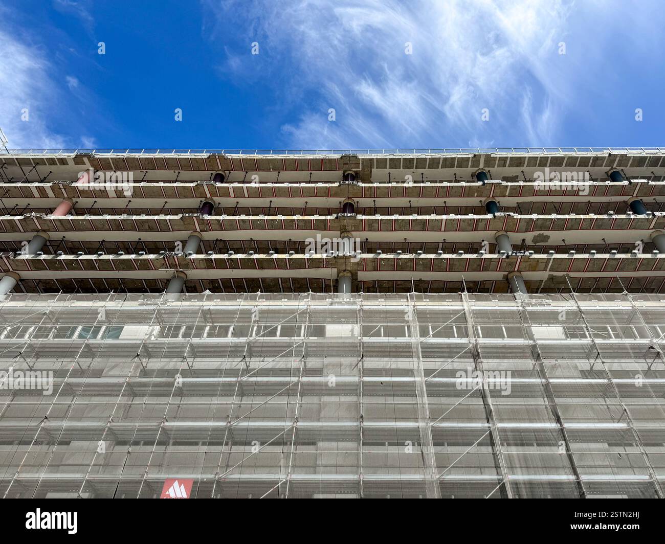 Costruzione di edifici, sistema di ponteggi su una struttura alta, vista ad angolo basso, cielo blu Foto Stock