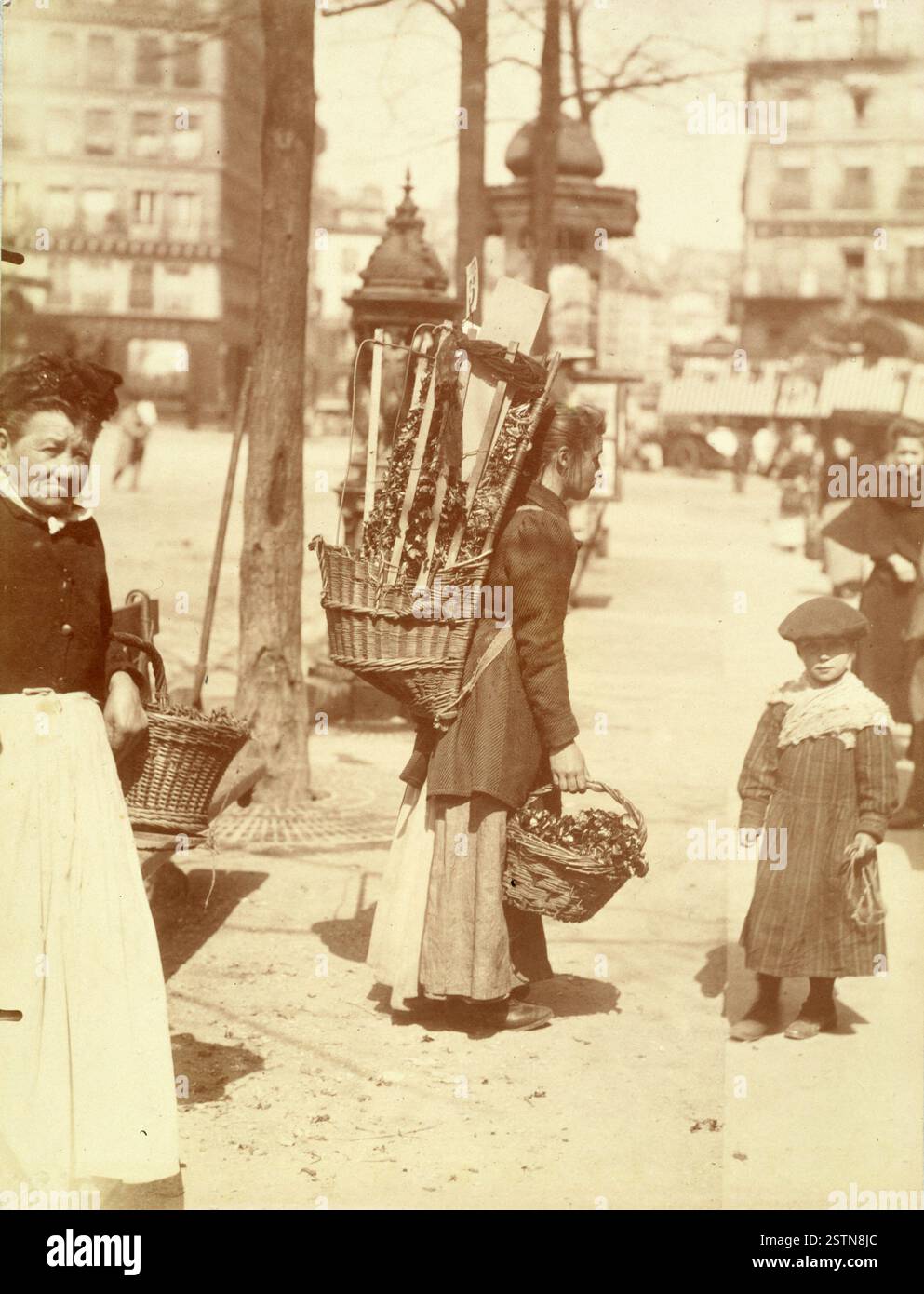 Marchande de cresson, Avenue des Gobelins, Parigi, 1898. Eugène Atget cattura una donna e un bambino che vendono un crescione di fronte a una colonna di Morris e a una fontana di Wallace. Questa scena riflette i venditori della classe operaia di Parigi. Foto Stock