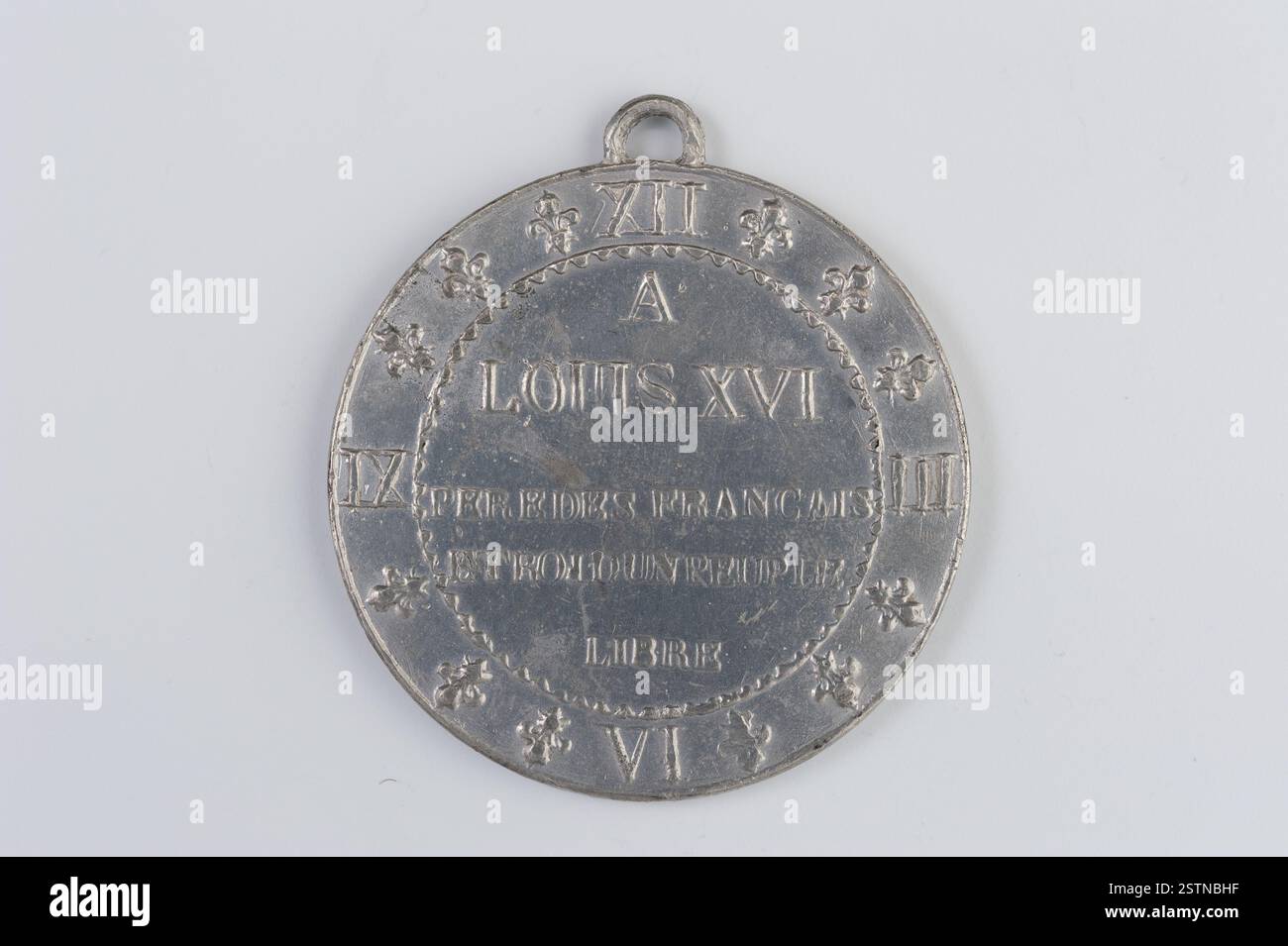 Questa moneta del XVIII secolo raffigura un orologio con numeri romani III, vi, IX e XII, con fleurs-de-lys che sostituiscono gli altri marcatori orari, simboleggiando la monarchia. Il retro include un'iscrizione su quattro righe. Foto Stock