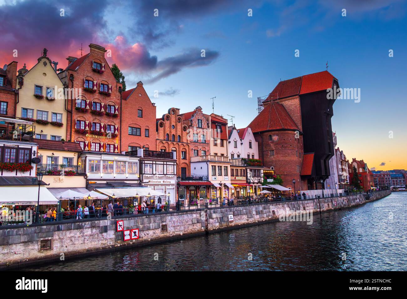 Incredibile tramonto colorato nel centro della città di Danzica, Polonia. Una vista serale di Motlawa, una riva del fiume, tipica architettura colorata e la Crane. Foto Stock