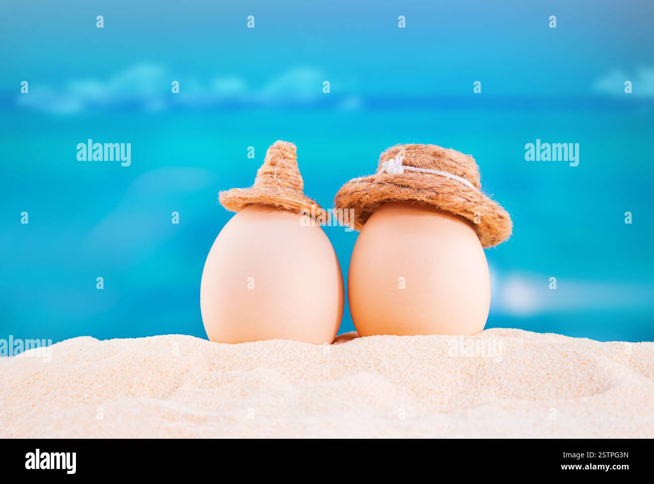 Buona pasqua. Uova bianche con cappelli sulla spiaggia sabbiosa del mare o dell'oceano. Cartolina natalizia in un paese caldo. Viaggi, primavera, estate, vacanze. Copia spazio Foto Stock