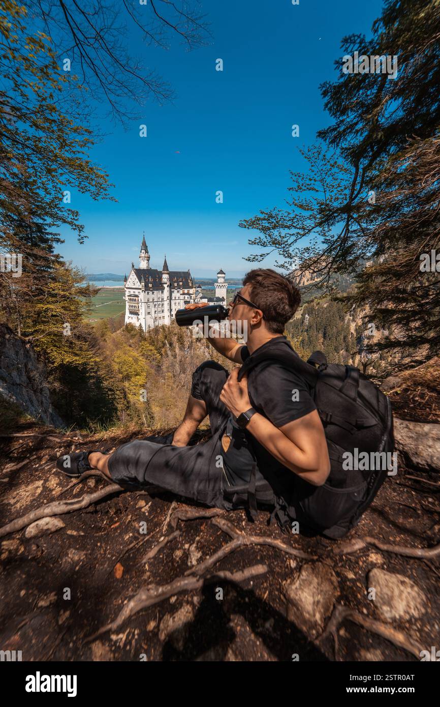 Guy beve acqua sul castello di collina sullo sfondo Foto Stock