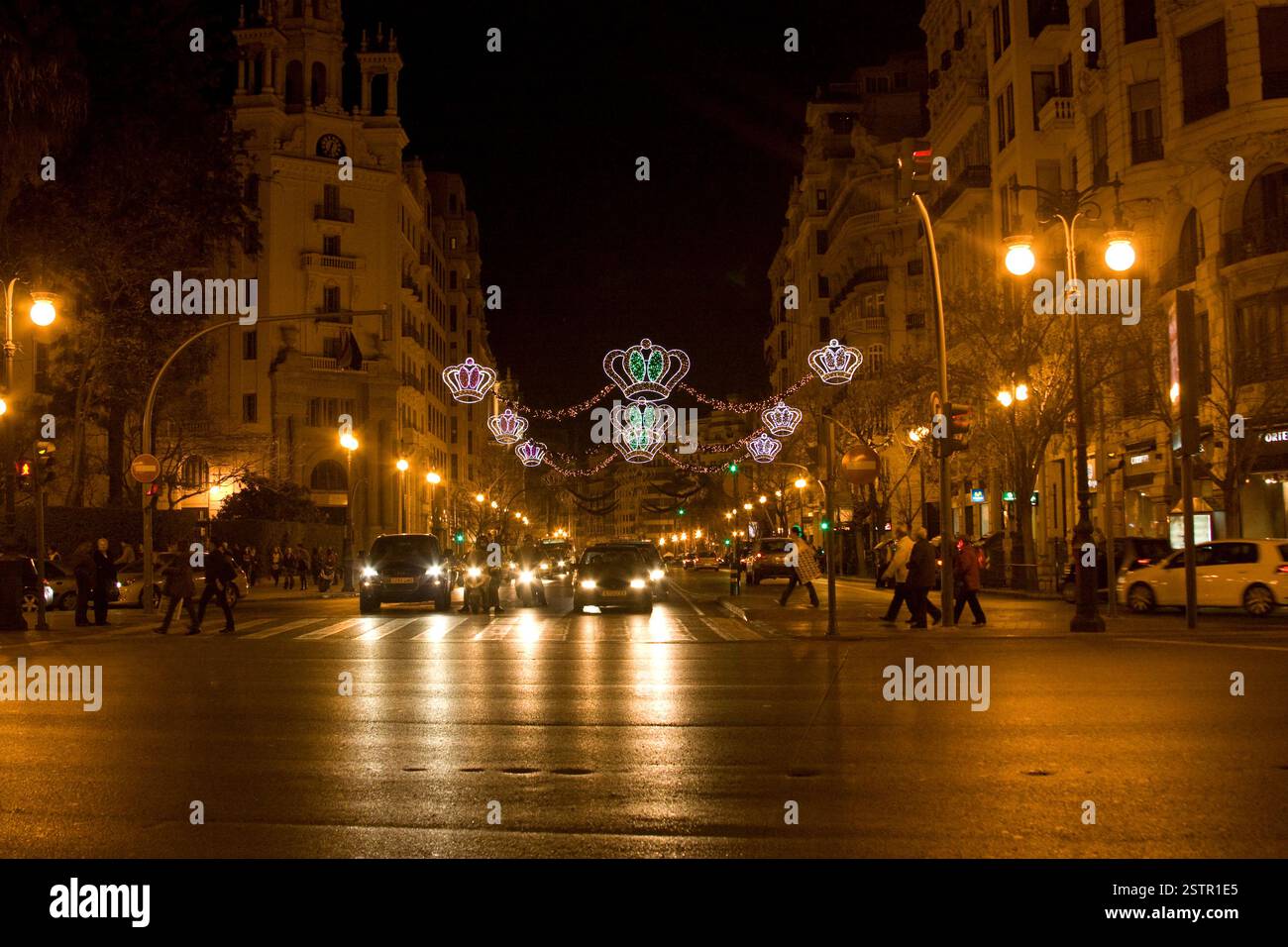 Strada della città di notte con auto e persone che attraversano. Vita urbana, scena notturna, illuminazione, decorazioni natalizie, strade illuminate Foto Stock