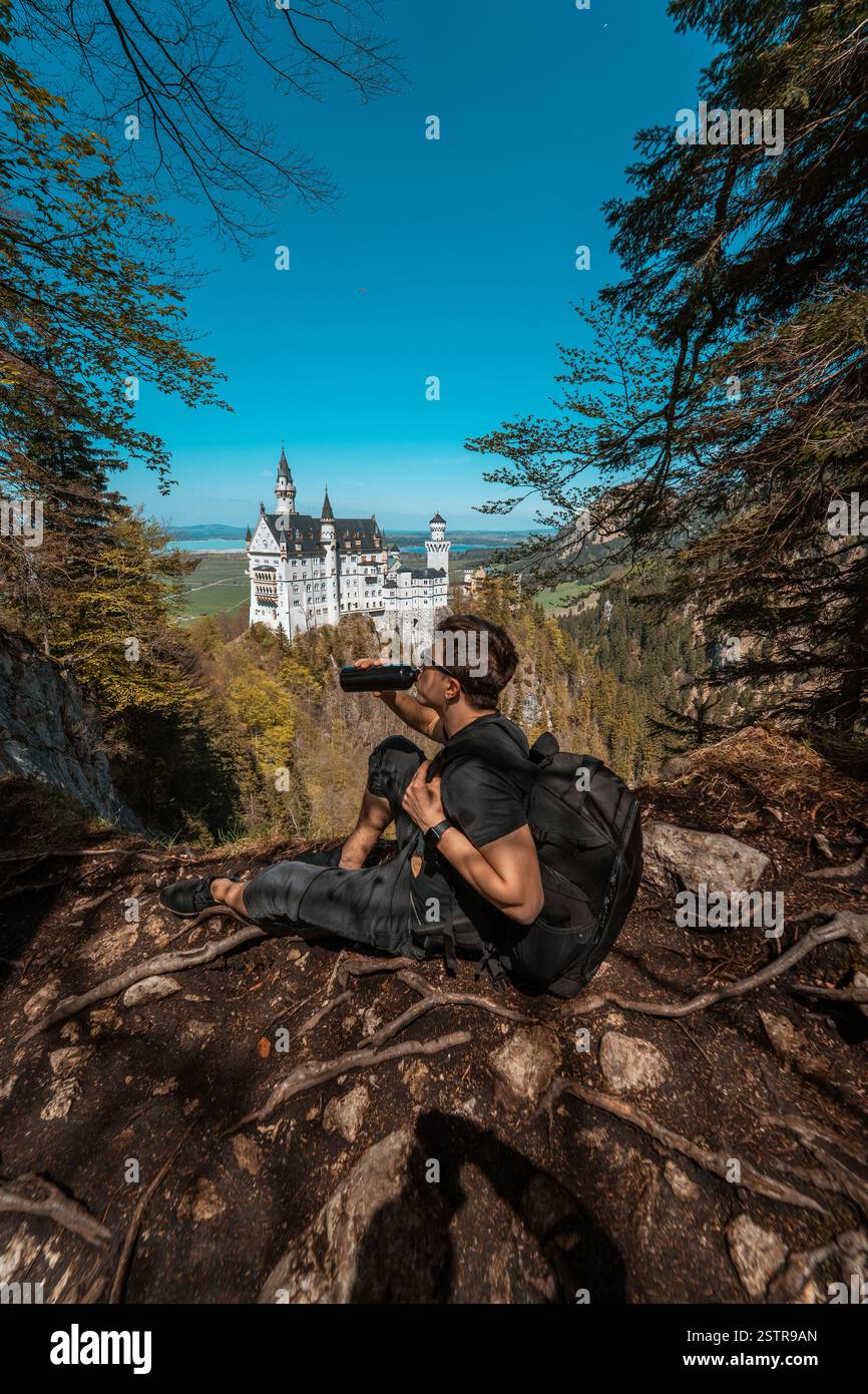 Guy beve acqua sul castello di collina sullo sfondo Foto Stock