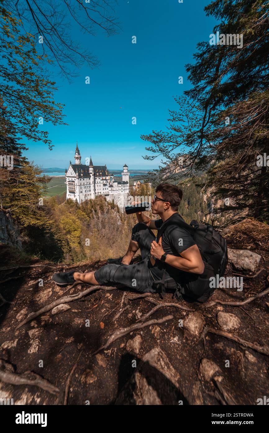 Guy beve acqua sul castello di collina sullo sfondo Foto Stock