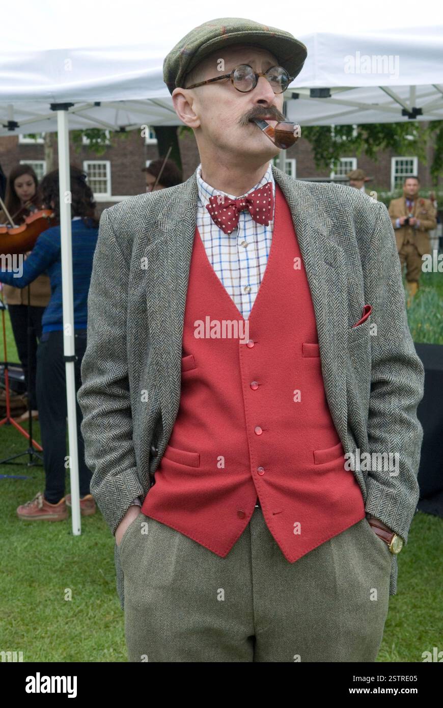 Stile retrò vecchio stile, l'uomo indossa un cappello in tweed e un abito con un gilet rosso e un papillon maculato rosso e bianco. Sta fumando una pipa. Londra Inghilterra anni '2014 2010 Regno Unito HOMER SYKES Foto Stock