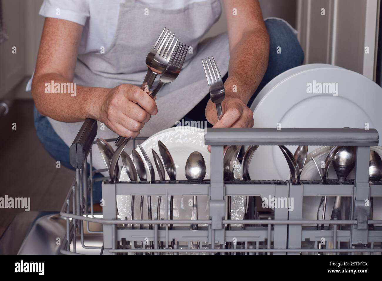 La donna sta scaricando le posate da una lavastoviglie in cucina Foto Stock