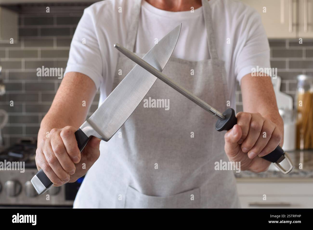 La donna sta affilando un coltello in una cucina di casa Foto Stock
