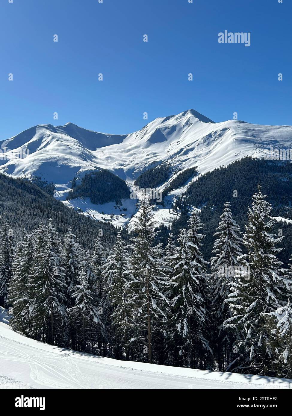 Maestose vette montane sotto un cielo azzurro cristallino! Montagne innevate che brillano al sole d'inverno. - Immagine stock catturata con smartphone