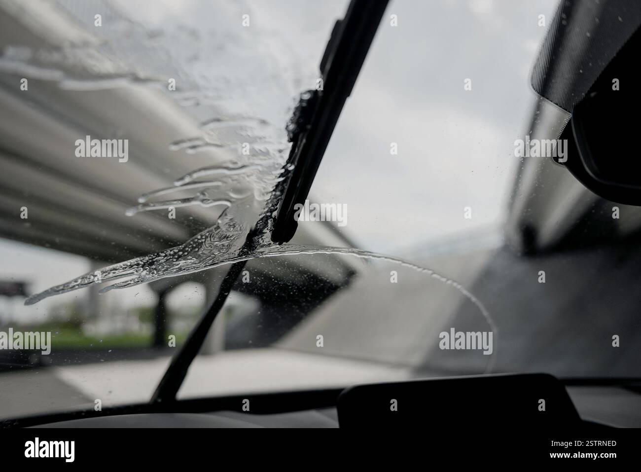 Tergicristalli al lavoro - guida di un'auto sotto la pioggia. Punto di vista del conducente: I tergicristalli rimuovono l'acqua dalla superficie del cristallo durante la guida. Foto Stock