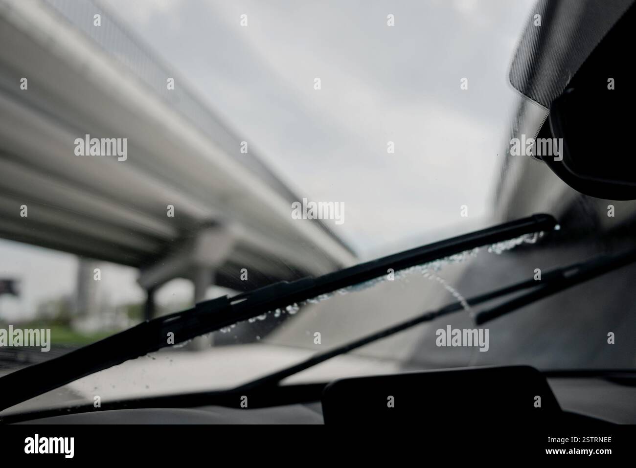 Tergicristalli che rimuovono l'acqua dalla superficie del vetro. Il punto di vista del conducente della guida di un'auto sotto la pioggia: I tergicristalli funzionano durante la guida. Foto Stock
