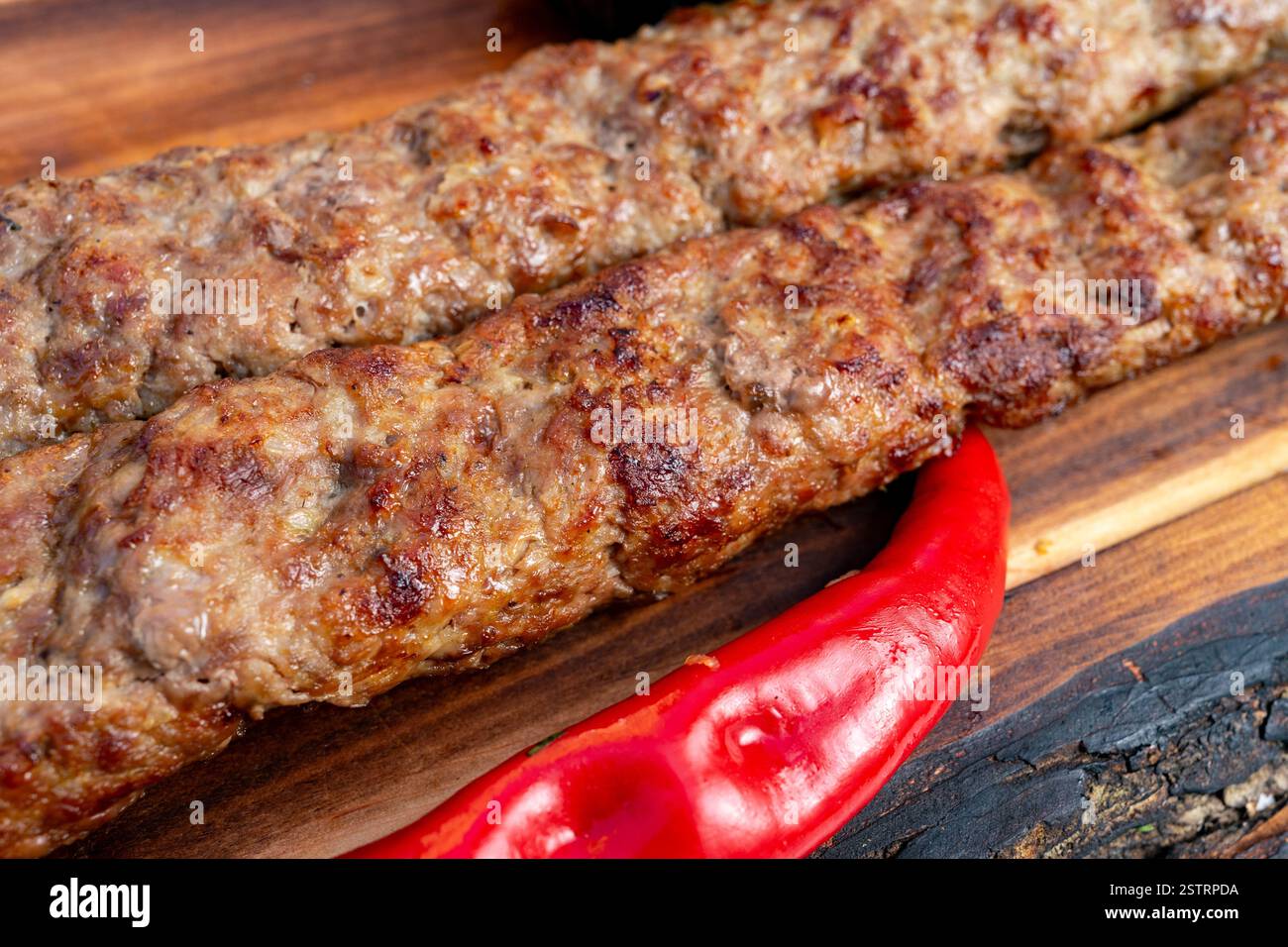 Due succosi kebab sono grigliati alla perfezione, accompagnati da un vivace peperoncino rosso. Foto Stock