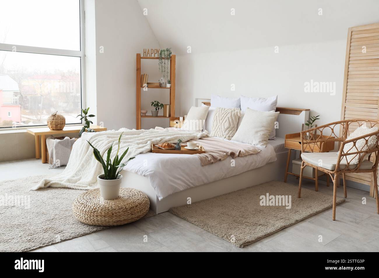 Interni eleganti di una comoda camera da letto moderna con un comodo letto e una pianta di casa sul pouf Foto Stock
