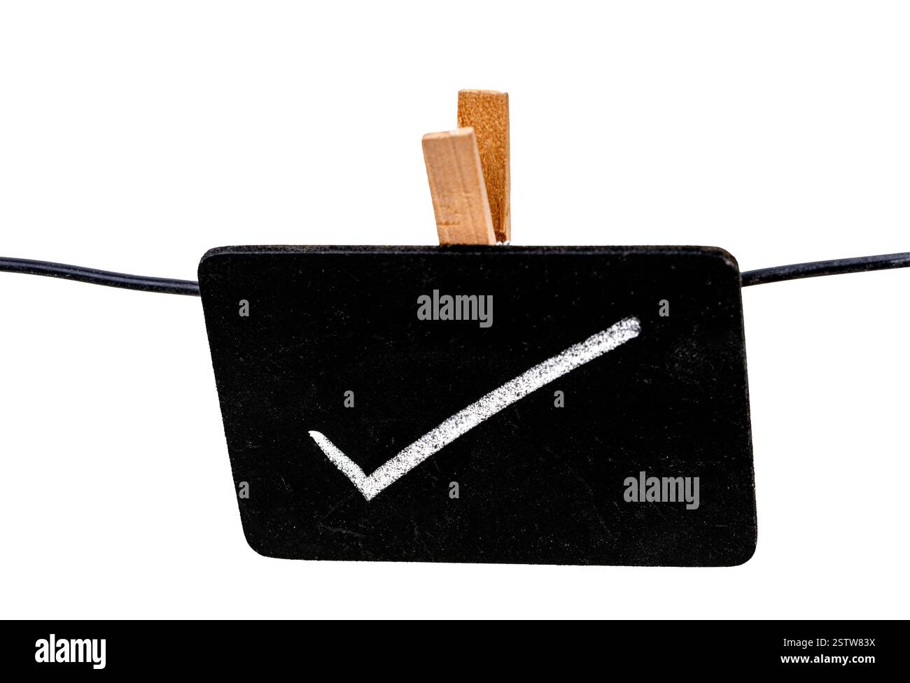 Segno di approvazione: Un primo piano di un piccolo cartello in stile lavagna con un segno di spunta disegnato a mano, tenuto saldamente in posizione da un clothespin di legno, d Foto Stock