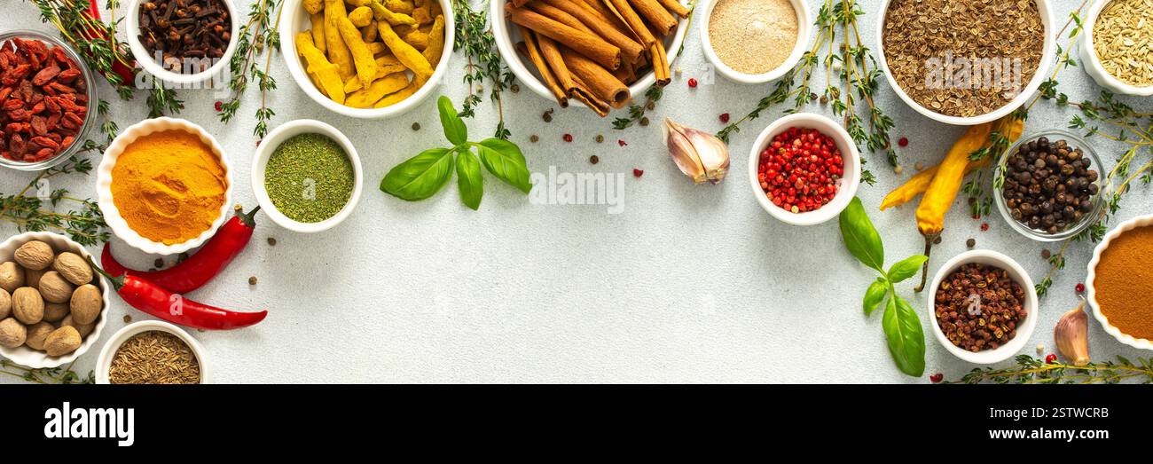 Erbe e spezie colorate e fresche incorniciano uno sfondo grigio, un bordo naturale perfetto per attirare l'attenzione sulla creatività culinaria, vista dall'alto, spazio copia, Foto Stock