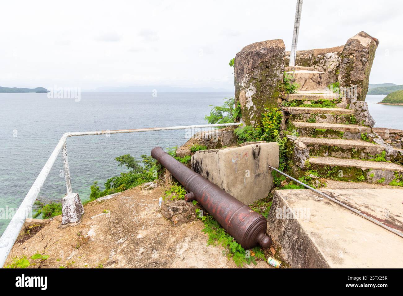 Resti del bastione della chiesa della fortezza di Culion con un vecchio cannone di ferro su un promontorio che si affaccia sul mare a Culion, Palawan, Filippine Foto Stock