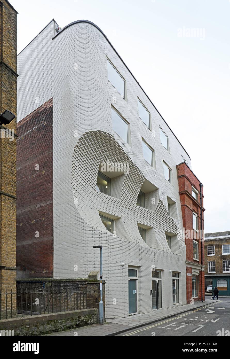 The Scoop, un nuovo edificio per uffici in o'Meara Street, Londra, Regno Unito. Edificio bianco in mattoni con una caratteristica paletta per proteggere la vista del rosone della chiesa. Foto Stock