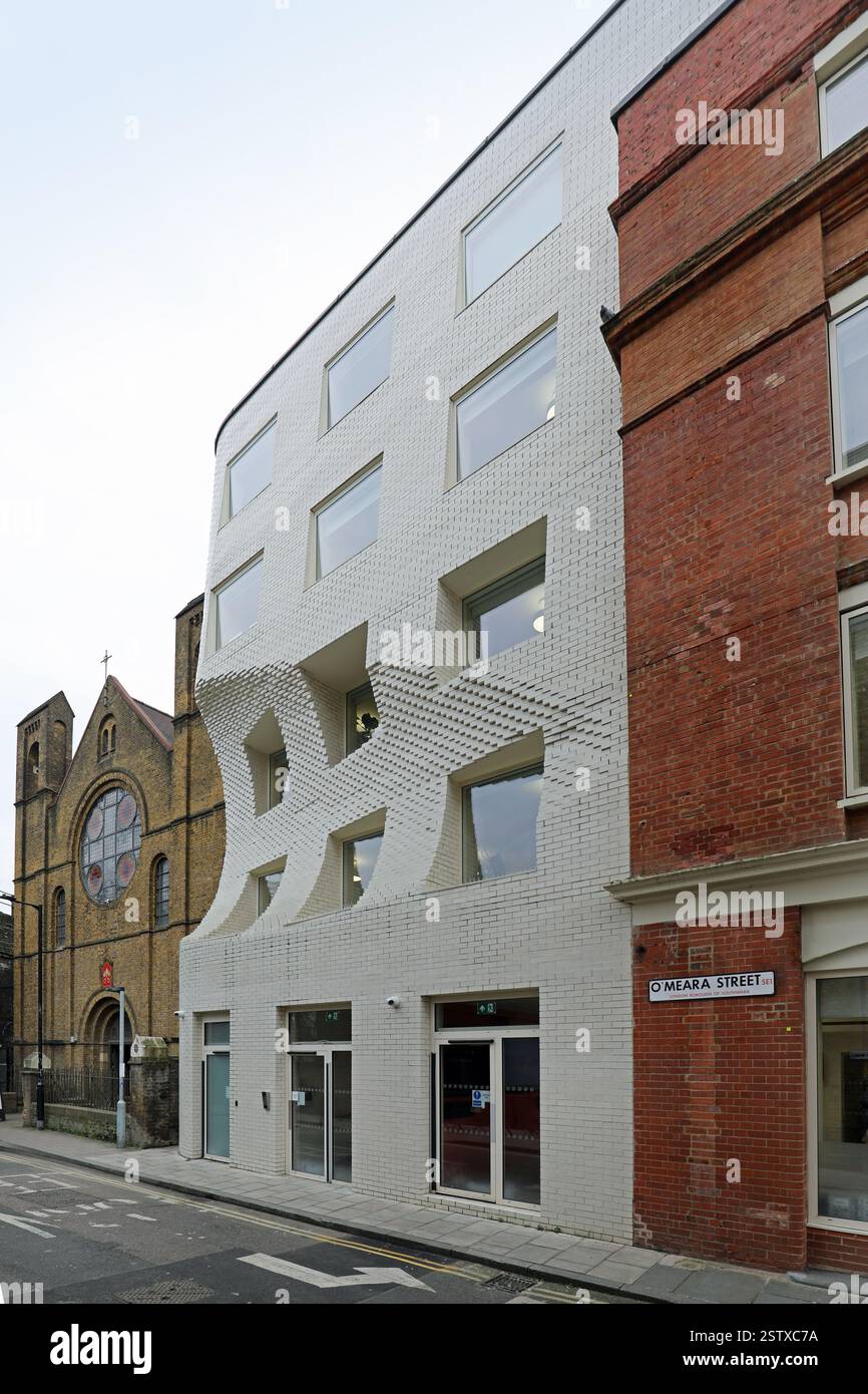 The Scoop, un nuovo edificio per uffici in o'Meara Street, Londra, Regno Unito. Edificio bianco in mattoni con una caratteristica paletta per proteggere la vista del rosone della chiesa. Foto Stock