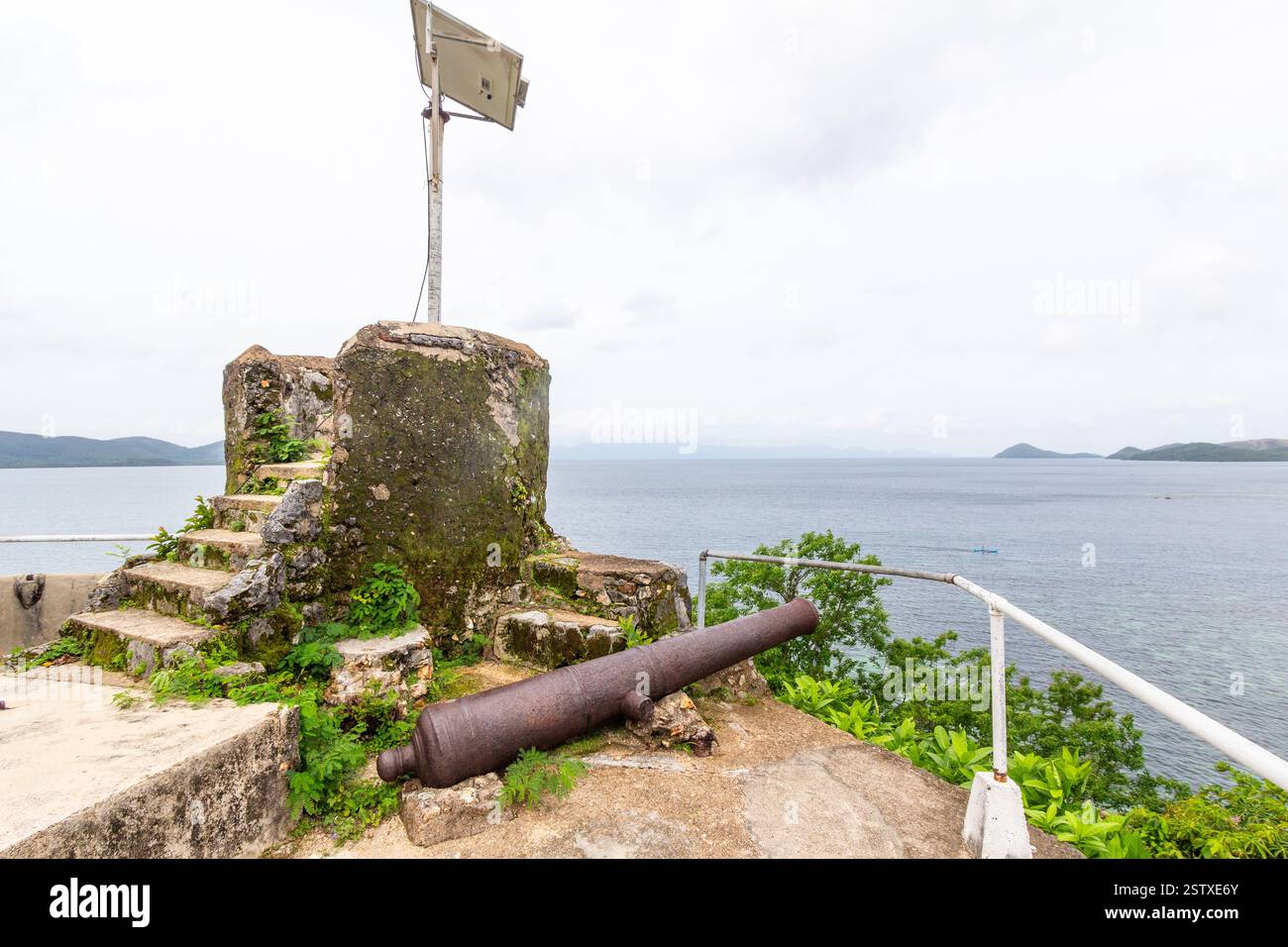 Resti del bastione della chiesa della fortezza di Culion con un vecchio cannone di ferro su un promontorio che si affaccia sul mare a Culion, Palawan, Filippine Foto Stock